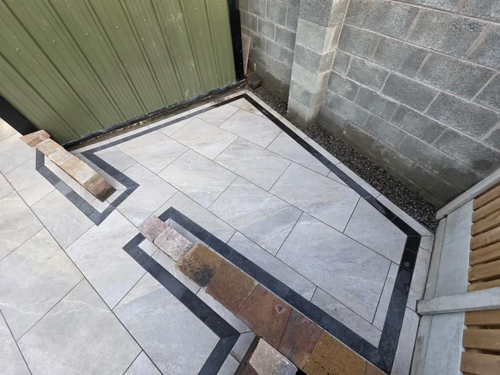 Porcelain paving leading to the garden building, framed by dark edging.