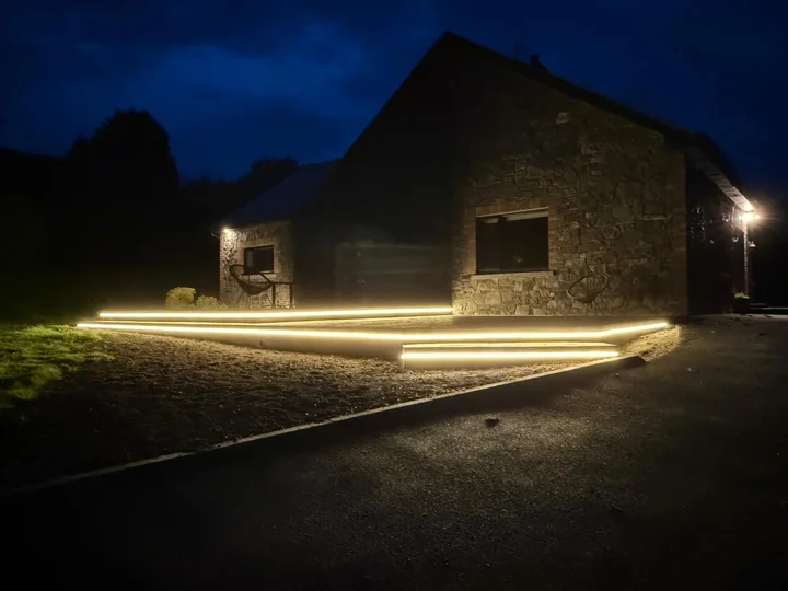 Warm lighting along the broad patio steps beside the stone house