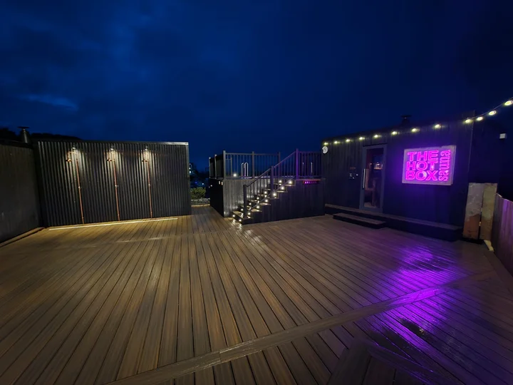 The broad composite deck beside the sauna buildings at dusk.